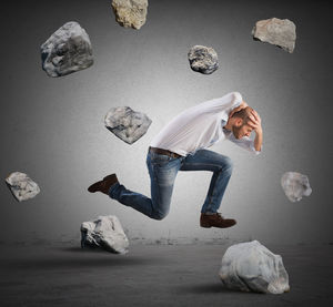 Digital composite image of man painting on rock against wall