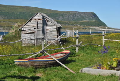 Boat against hut on landscape against clear sky