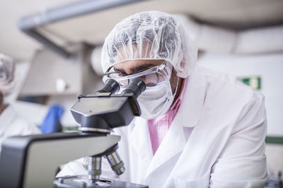 Man scientist looking through microscope at laboratory