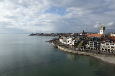 Buildings in sea against cloudy sky