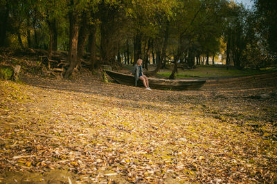 Boy on tree in forest during autumn