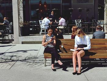 People sitting on seat in city