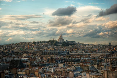 Aerial view of cityscape against cloudy sky