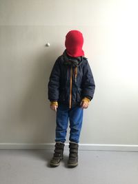 Boy covering face with knit hair against wall