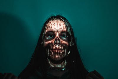 Close-up of spooky woman against blue background