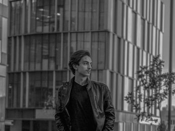 Portrait of young man standing against buildings