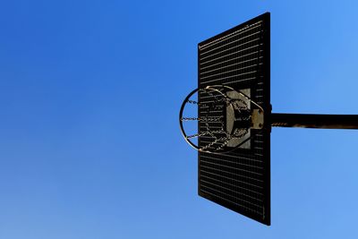 Directly below shot of basketball hoop against clear blue sky on sunny day