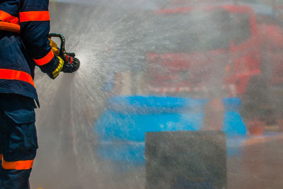 Midsection of firefighter holding hose