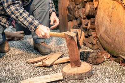 Man uses ax to break wood to use for bbq wood to light fire to cook food on grill hands holding tool