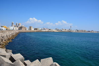 Sea by buildings against blue sky