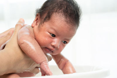 Cropped hand of parent holding baby girl in bathroom