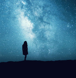Rear view of silhouette woman standing against star field
