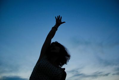 Low angle view of woman with arms raised against sky