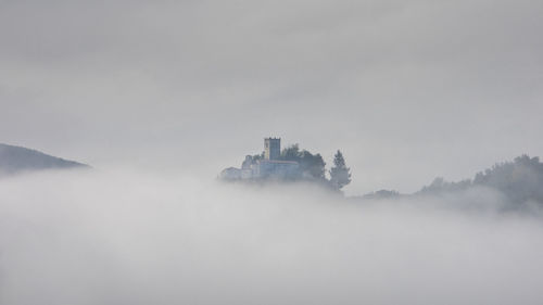 Distant view of castle against sky during foggy weather