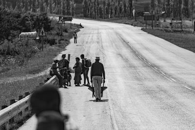 Rear view of people walking on road in city