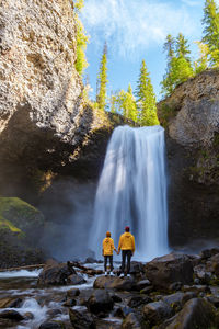 Rear view of man standing against waterfall