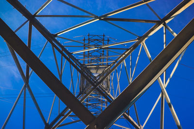 Low angle view of electricity pylon against clear blue sky