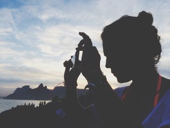 Woman photographing against sky