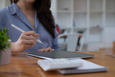 Midsection of woman using mobile phone while sitting on table