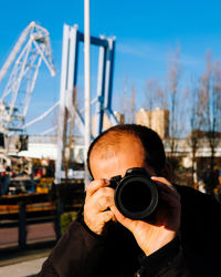 Portrait of man photographing against sky
