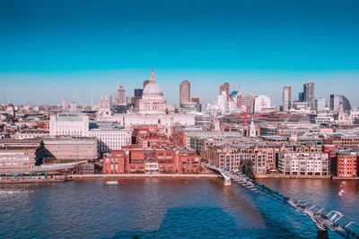View of city at waterfront against blue sky