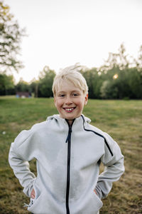 Portrait of smiling boy standing with hands in pockets at playground