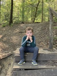 Portrait of boy sitting in forest