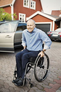Portrait of happy man sitting in wheelchair on street
