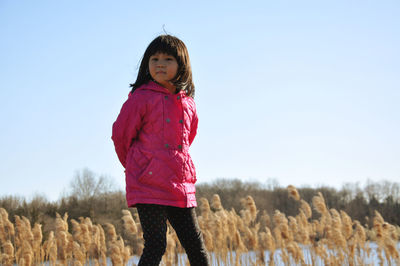 Full length of girl standing on field against clear sky