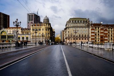 Road amidst buildings in city against sky