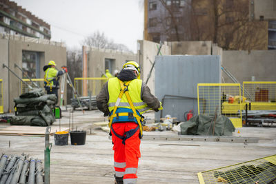 Rear view of male builder construction worker on building site wearing hard hat and hi-vis vest