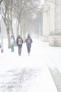 Rear view of people walking on snow covered street