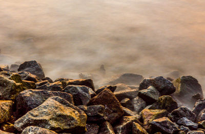 Close-up of rocks in sea against sky