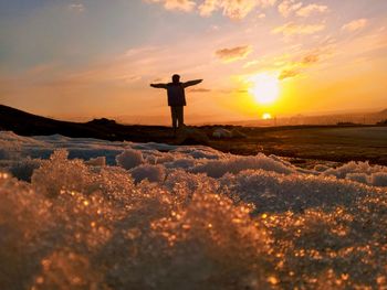 Silhouette person standing on field against sky during sunset