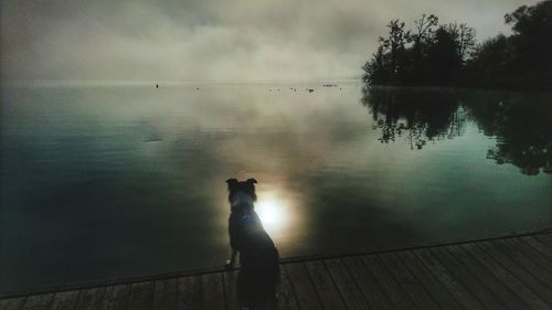 Man standing by lake against sky