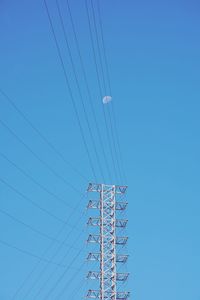 Low angle view of electricity pylon against clear blue sky