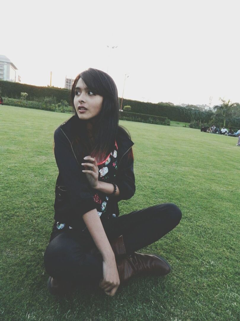 grass, lifestyles, young adult, leisure activity, person, casual clothing, young women, portrait, full length, looking at camera, sitting, grassy, smiling, standing, front view, field, park - man made space, long hair