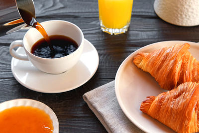 Coffee cup with croissant on a rustic dark wooden table. food series. two tasty fresh croissants