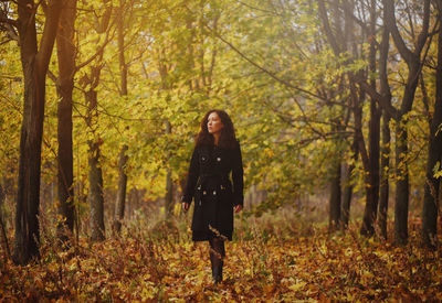 Full length of young woman standing in forest