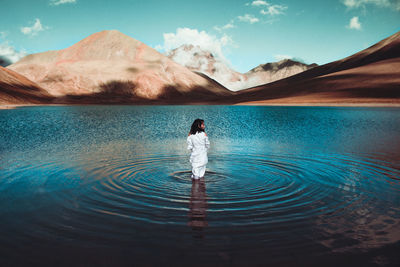 Rear view of man in lake against sky