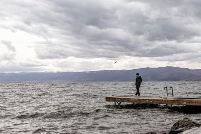 Man standing on shore against sky