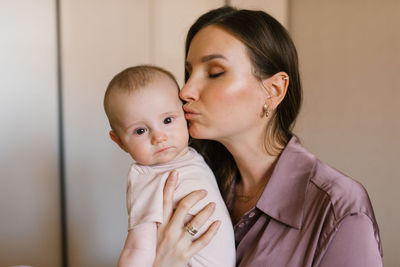 Mother lifts the baby up in her arms, kissing him on the cheek