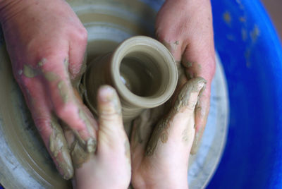 Cropped hands of people making clay pot