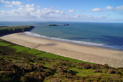 Gower peninsular rhossilli bay panoramic with green hills surrounding the sandy bay 