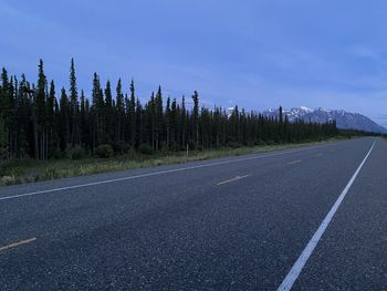 Road by trees against sky