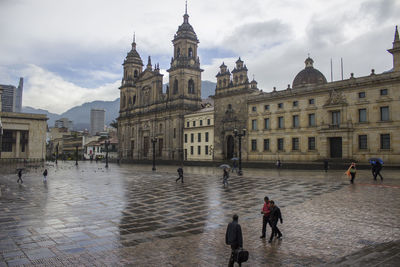 People at bolivar square by primatial cathedral of bogota against sky