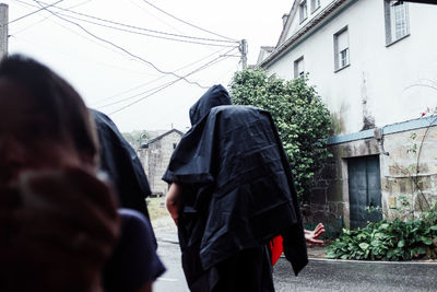 Rear view of people walking on building during rainy season