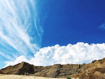 Low angle view of clouds over mountain against sky