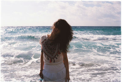 Woman standing at beach against sky