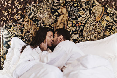Couple kissing while lying on bed in hotel room